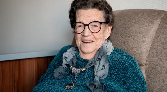 ''Mevrouw Huijbers-Kuiper glimlacht naar de camera vanuit haar stoel, thuis in Anna Paulowna.''