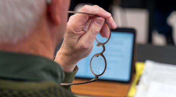 Detailfoto van één van de cliëntenraadsleden van Omring die naar een tablet kijkt.