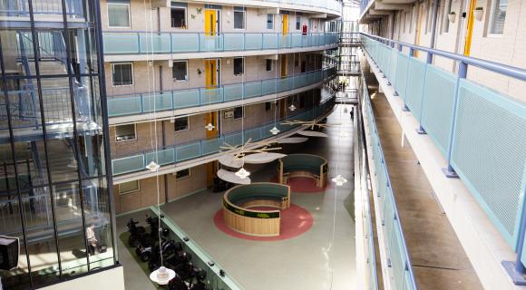 Centrale binnentuin en galerijen van woonlocatie Betsy Perk in Hoorn, met appartementen, liften en ontmoetingsruimtes.