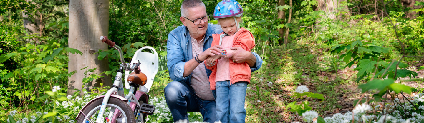 Campagnebeeld van Omring thuiszorg: opa die een pleister plakt op de wond van zijn kleinzoon.