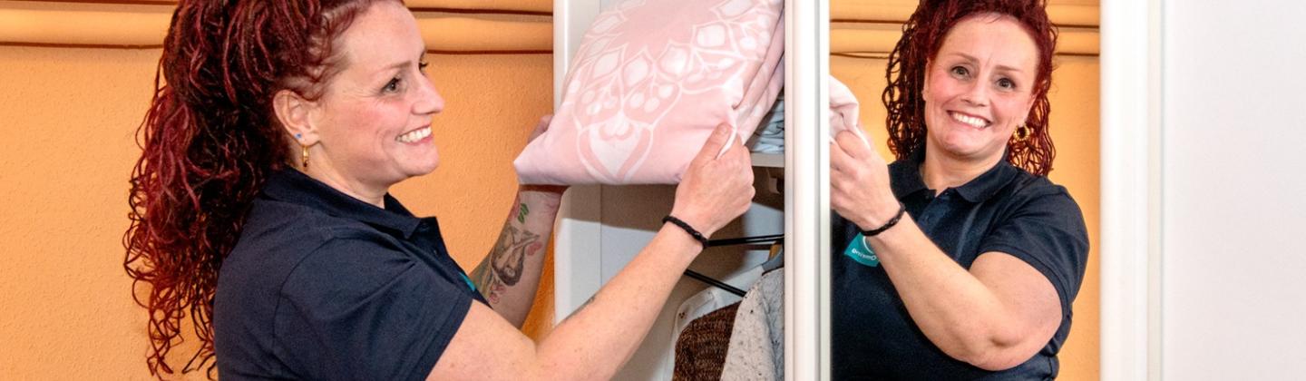 Een medewerker van HulpThuis haalt beddengoed uit de kast.