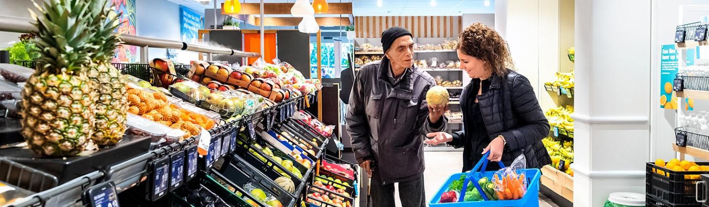 De thuisbegeleider is samen met een cliënt aan het boodschappen doen in de supermarkt.