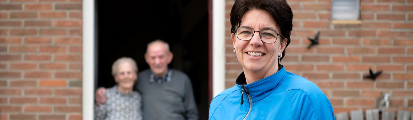 Thuiszorgmedewerker voor de deur bij een echtpaar.