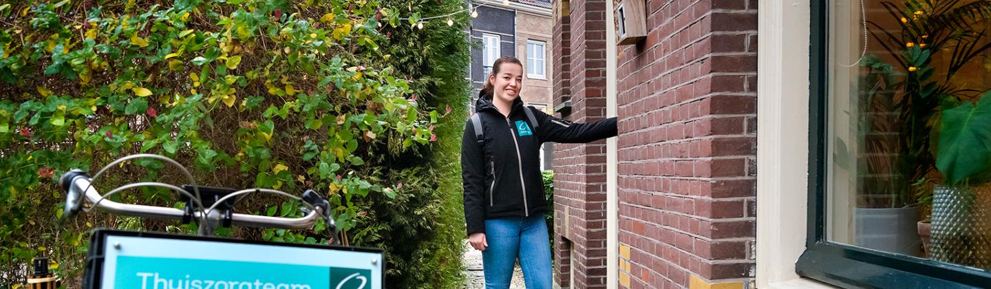 Een medewerker van thuiszorgteam Bovenkarspel belt aan bij een woning.