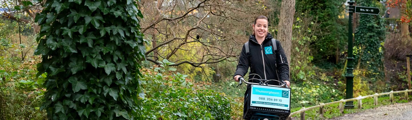 De wijkverpleegkundige fietst door het Snouck van Loosenpark in Enkhuizen.