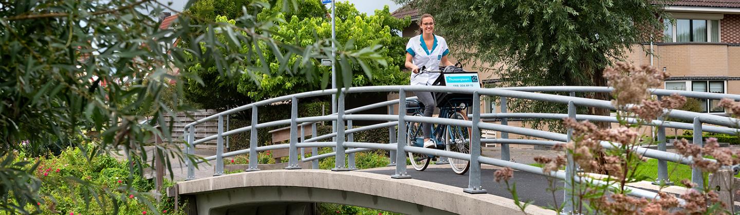Verpleegkundige van Omring thuiszorg fietst door Hoogkarspel.