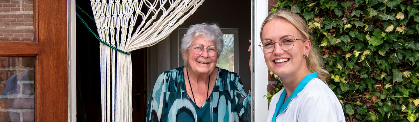 Medewerker van de Omring thuiszorg staat bij een mevrouw aan de deur.