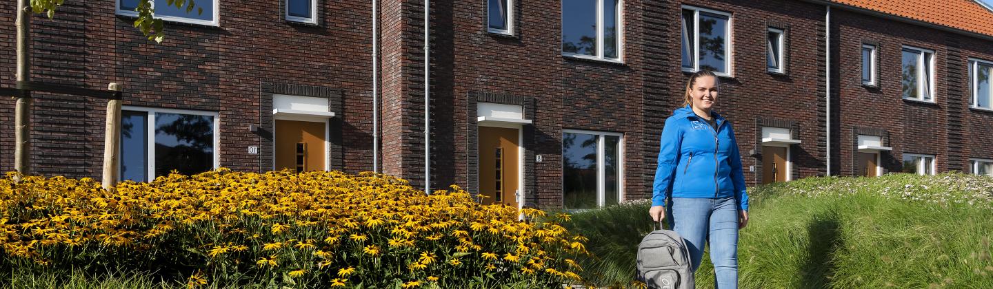 Medewerker van thuiszorgteam Wieringermeer is op weg naar een cliënt en wandelt door de wijk.