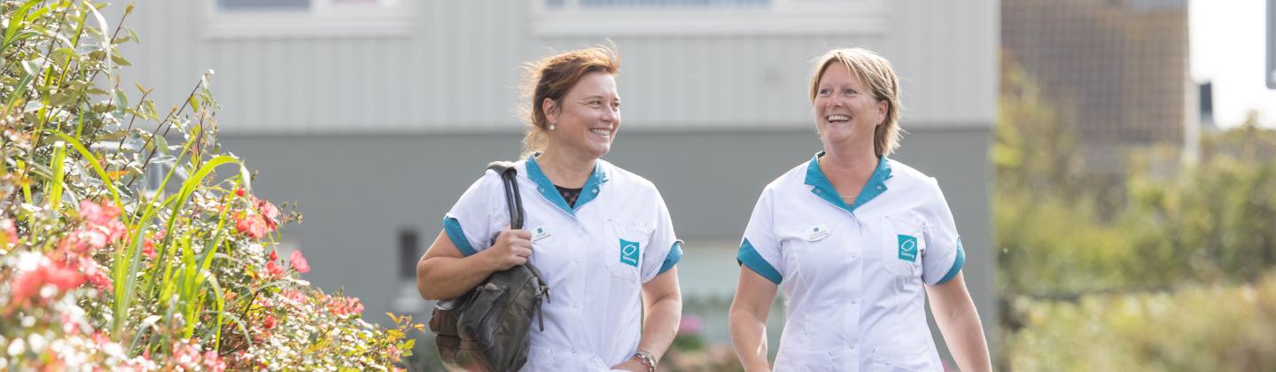 Twee verpleegkundigen van thuiszorgteam Zijpe wandelen door de wijk.