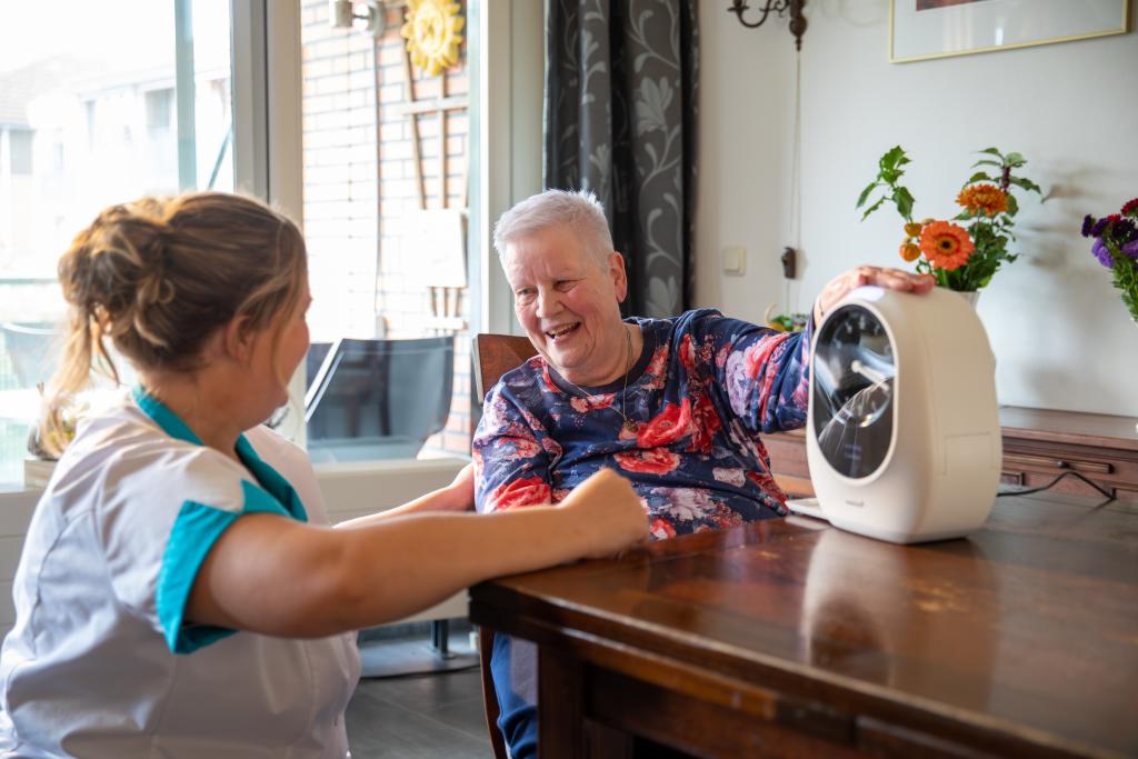 Wijkverpleegkundige en cliënt met de medicijndispenser