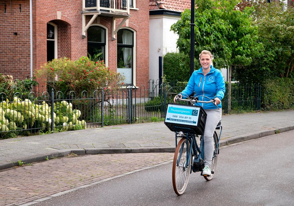 Medewerker van de thuiszorg op de fiets in een woonwijk.