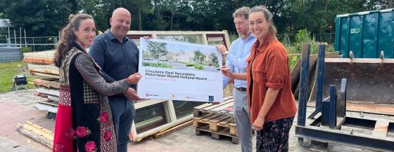 Medewerkers Omring en Van Wijnen staand voor geoogste bouwmaterialen