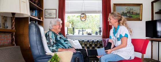 Medewerker van de thuiszorg van Omring helpt een cliënt thuis met steunkousen.