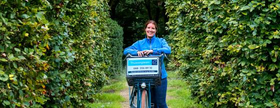 Medewerker van de Omring thuiszorg staat leunend op haar fiets.