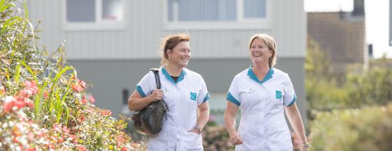 Twee verpleegkundigen van thuiszorgteam Zijpe wandelen door de wijk.
